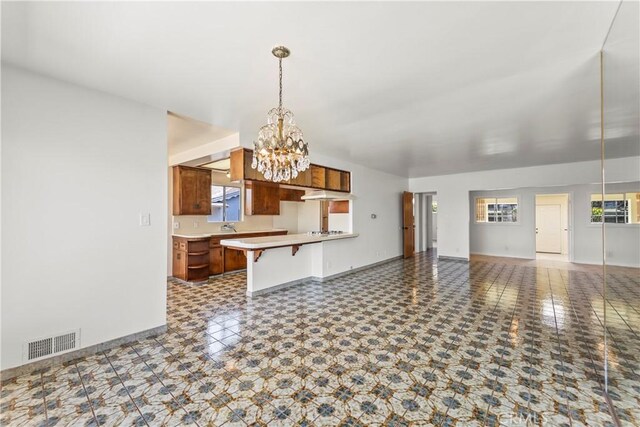2021 Elanita Dr, San Pedro, CA 90732 - kitchen featuring a chandelier, open floor plan, a breakfast bar area, brown cabinetry, and healthy amount of natural light