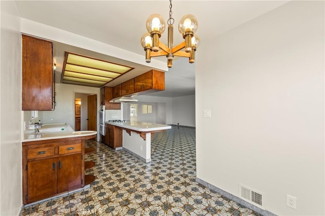 2021 Elanita Dr, San Pedro, CA 90732 - kitchen featuring a chandelier, under cabinet range hood, light countertops, dark floors, and baseboards