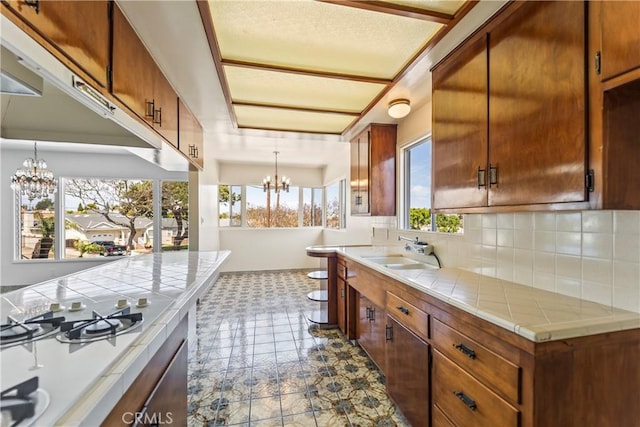 2021 Elanita Dr, San Pedro, CA 90732 - kitchen featuring a chandelier, tile counters, a sink, decorative backsplash, and dark flooring