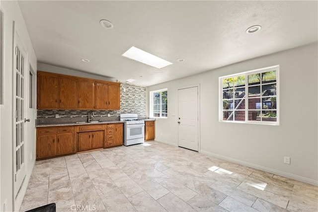 2021 Elanita Dr, San Pedro, CA 90732 - kitchen featuring white range with gas stovetop, brown cabinets, tasteful backsplash, a skylight, and a sink