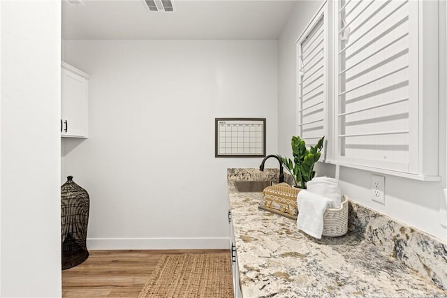 laundry room featuring light wood-type flooring, a sink, and baseboards