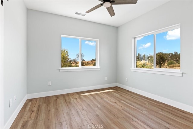 empty room with a ceiling fan, light wood finished floors, and baseboards
