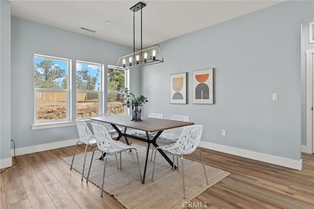 dining room featuring baseboards, plenty of natural light, light wood-style flooring, and a chandelier