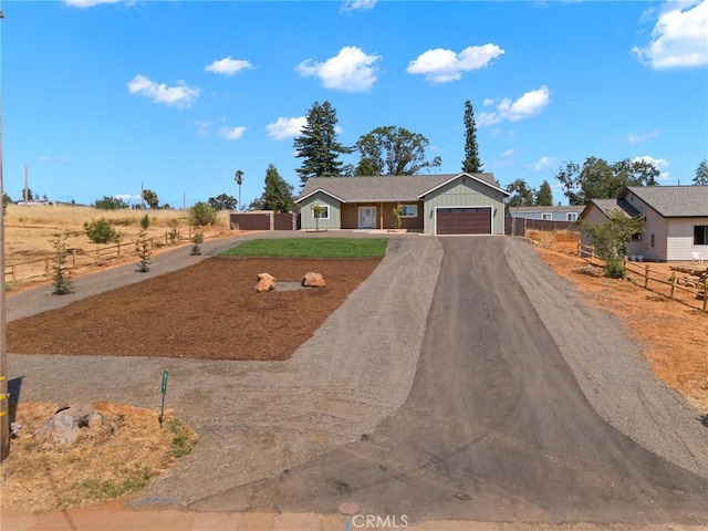 single story home with a garage, fence, driveway, and board and batten siding