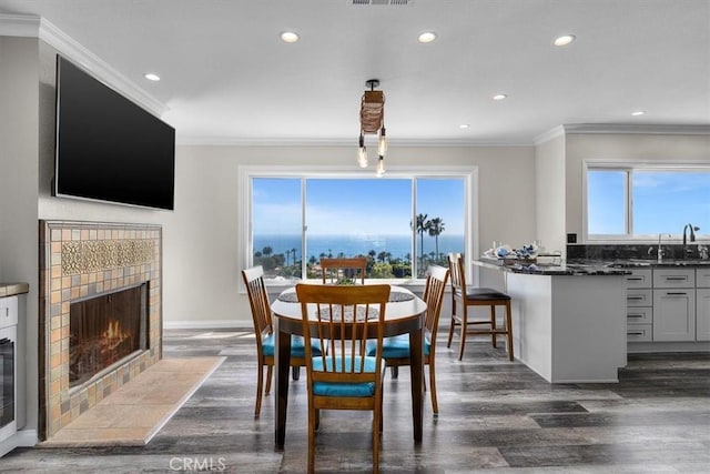 3602 S Walker Ave, San Pedro, CA 90731 - dining area featuring dark wood-type flooring, crown molding, a tile fireplace, recessed lighting, and baseboards