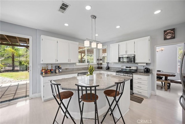 2 Corte Lateuza, Lake Elsinore, CA 92532 - kitchen with stainless steel appliances, white cabinets, a breakfast bar, recessed lighting, and light stone counters