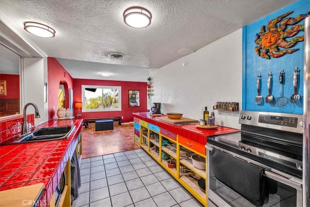 56772 Kismet Rd, Yucca Valley, CA 92284 - kitchen with stainless steel electric range, tile countertops, a sink, a textured ceiling, and light tile patterned flooring