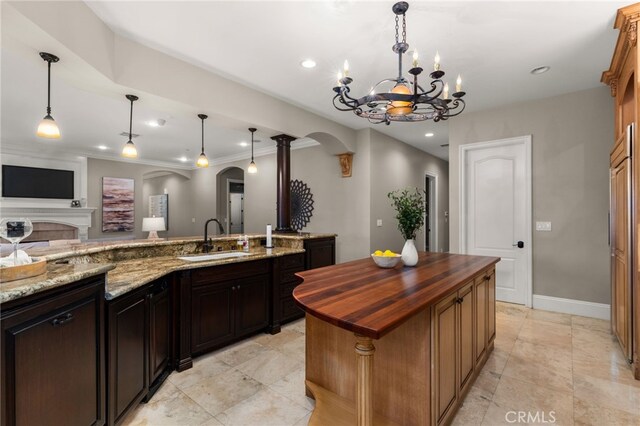 475 W 26th St, Upland, CA 91784 - kitchen featuring arched walkways, a sink, wood counters, a chandelier, and a center island