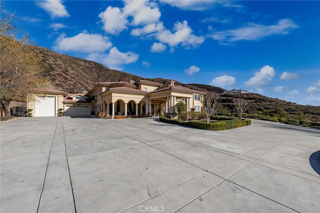 475 W 26th St, Upland, CA 91784 - mediterranean / spanish-style home with a mountain view, curved driveway, an attached garage, stucco siding, and a tile roof