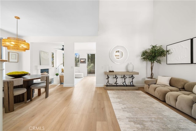 59 Cape Victoria, Aliso Viejo, CA 92656 - living area featuring a ceiling fan, a warm lit fireplace, light wood-style flooring, and a high ceiling