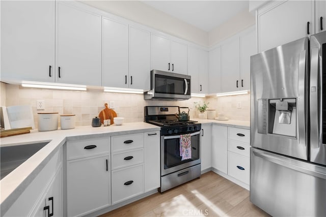 59 Cape Victoria, Aliso Viejo, CA 92656 - kitchen featuring stainless steel appliances, white cabinets, light wood-style floors, tasteful backsplash, and a sink