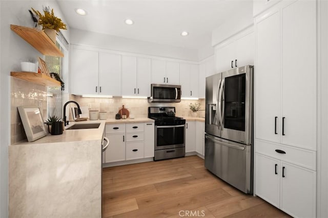 59 Cape Victoria, Aliso Viejo, CA 92656 - kitchen featuring appliances with stainless steel finishes, light countertops, light wood-style floors, decorative backsplash, and open shelves