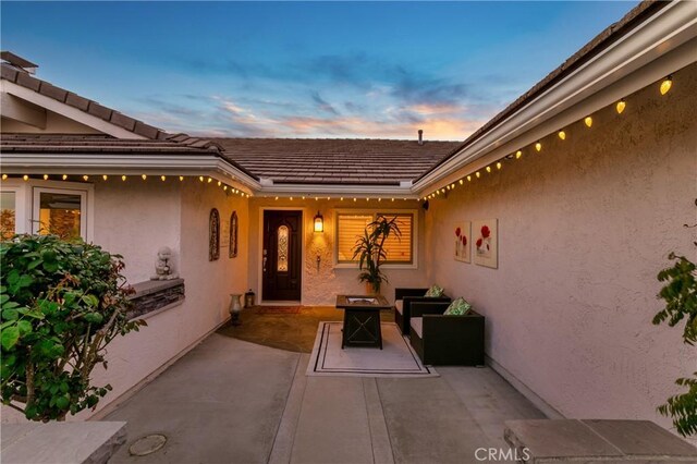 2546 N Orange Hill Ln, Orange, CA 92867 - exterior entry at dusk with a patio area, stucco siding, and a tiled roof