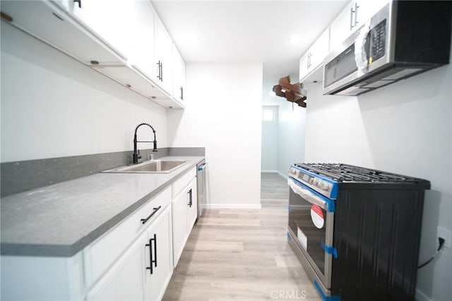 1336 W 118th St, Los Angeles, CA 90044 - kitchen with range with gas stovetop, a sink, stainless steel microwave, light wood-style floors, and white cabinetry