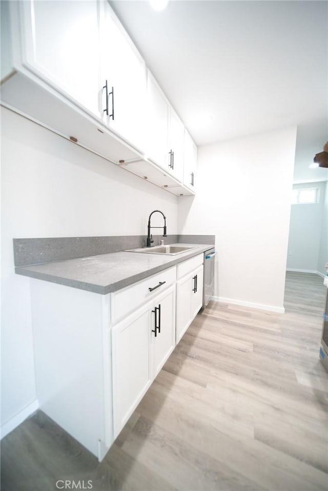 1336 W 118th St, Los Angeles, CA 90044 - kitchen featuring a sink, white cabinets, light wood-style flooring, baseboards, and dishwasher