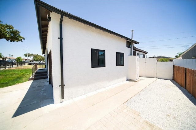 1336 W 118th St, Los Angeles, CA 90044 - view of property exterior with stucco siding, a patio, and a gate