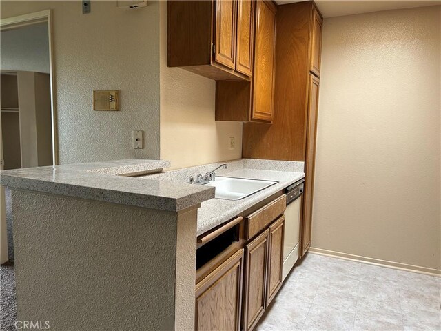 4499 Via Marisol Unit 327, Los Angeles, CA 90042 - kitchen with white dishwasher, brown cabinets, a textured wall, light countertops, and a peninsula