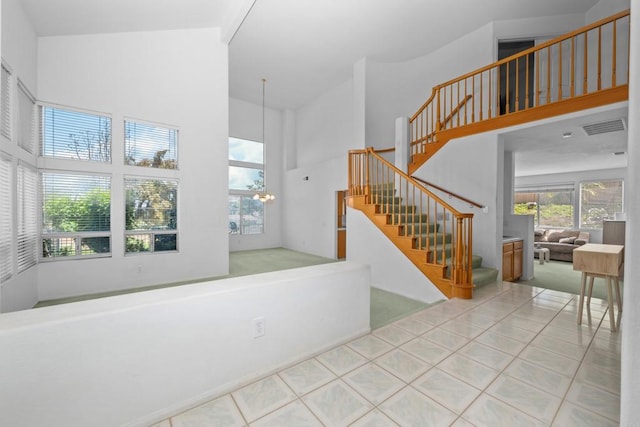 entryway featuring a towering ceiling, stairs, and tile patterned floors