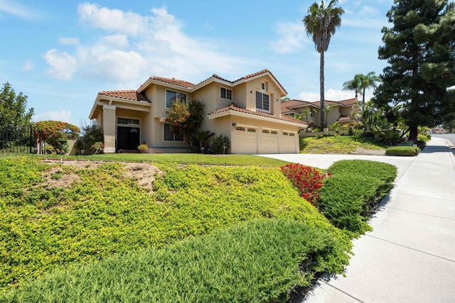 mediterranean / spanish home with an attached garage, stucco siding, a tile roof, and concrete driveway
