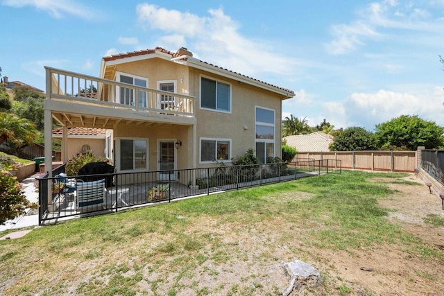 back of house with a tiled roof, stucco siding, and a balcony