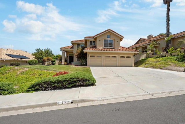 mediterranean / spanish house with a tile roof, driveway, an attached garage, and stucco siding