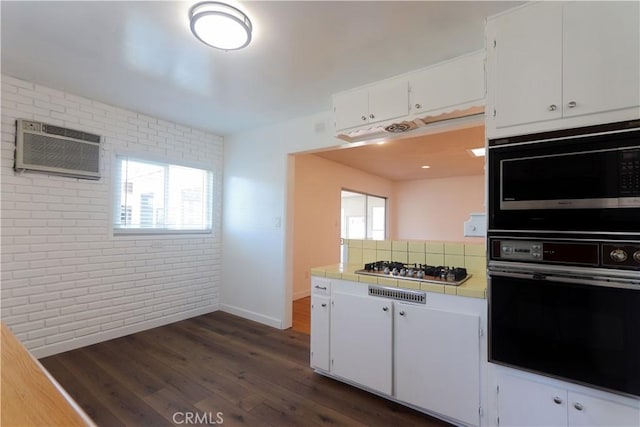 11618 Cedarvale St, Norwalk, CA 90650 - kitchen with black appliances, brick wall, tile counters, a wall unit AC, and white cabinets