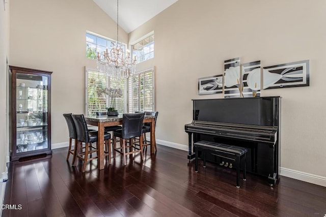 dining space with a chandelier, wood finished floors, baseboards, and high vaulted ceiling