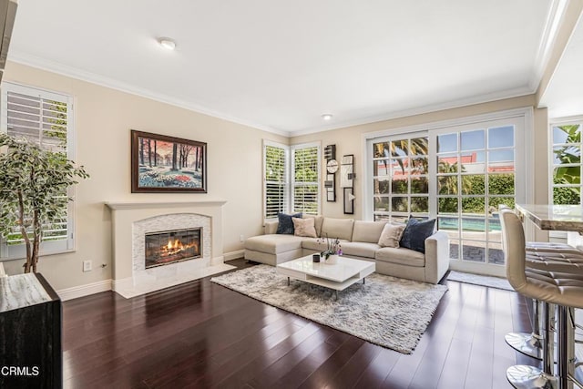 living area with baseboards, ornamental molding, a premium fireplace, and wood finished floors