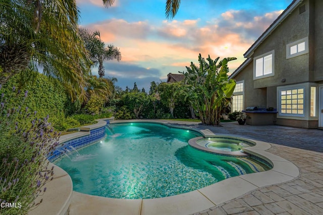 pool at dusk with a patio and a pool with connected hot tub