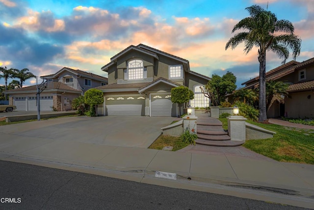 traditional-style home featuring an attached garage, stucco siding, and concrete driveway