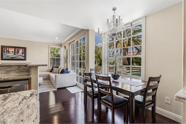 dining area featuring a chandelier, baseboards, dark wood finished floors, ornamental molding, and a textured wall