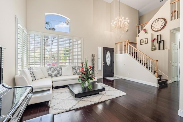 living area featuring stairs, a high ceiling, a chandelier, wood finished floors, and baseboards