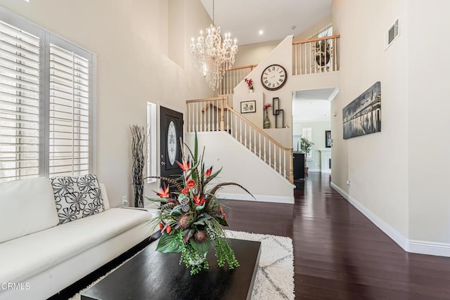 living area with stairway, a towering ceiling, wood finished floors, baseboards, and a chandelier