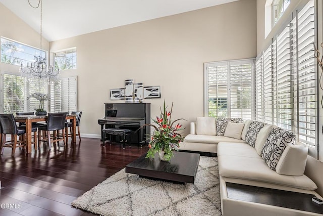 living area featuring a chandelier, high vaulted ceiling, wood finished floors, and baseboards
