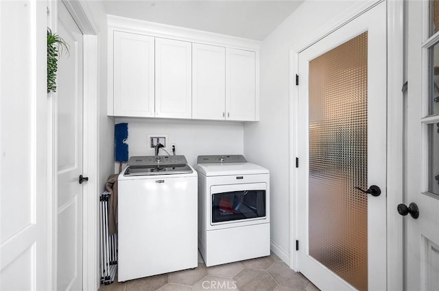 laundry room with washer and clothes dryer, cabinet space, and light tile patterned flooring