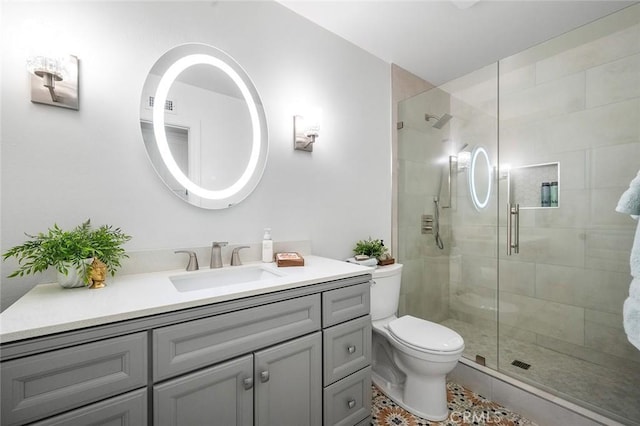 bathroom with a shower stall, toilet, vanity, and tile patterned floors