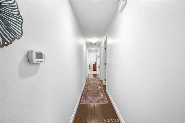 corridor with hardwood / wood-style floors, baseboards, and attic access