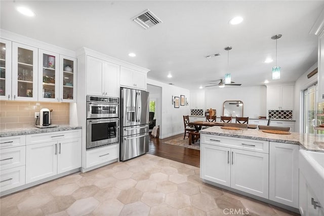 kitchen with appliances with stainless steel finishes, ceiling fan, tasteful backsplash, recessed lighting, and white cabinetry