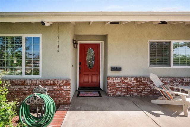 property entrance with stucco siding and brick siding