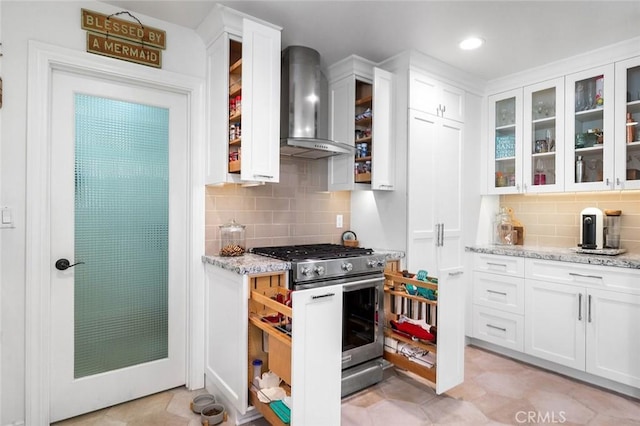 kitchen with wall chimney exhaust hood, high end stove, backsplash, white cabinetry, and recessed lighting