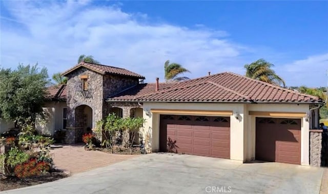 7940 Choi Dr, Riverside, CA 92506 - mediterranean / spanish-style house with stone siding, an attached garage, driveway, a tiled roof, and stucco siding