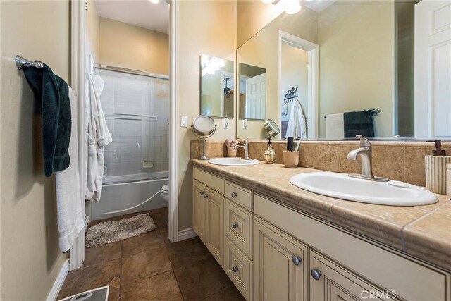 7940 Choi Dr, Riverside, CA 92506 - bathroom featuring double vanity, combined bath / shower with glass door, toilet, baseboards, and tile patterned floors