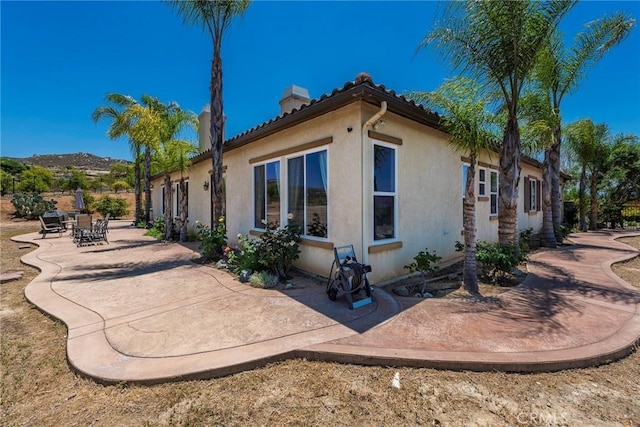 7940 Choi Dr, Riverside, CA 92506 - view of property exterior featuring stucco siding, a chimney, a patio area, and a tile roof