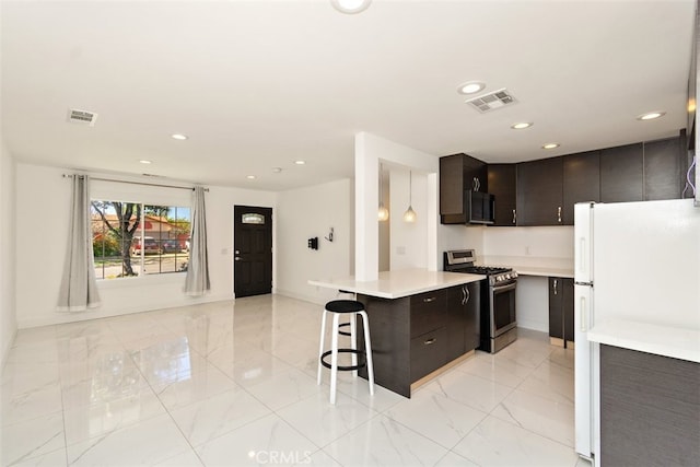 kitchen with stainless steel gas range oven, freestanding refrigerator, light marble finish flooring, light countertops, and recessed lighting