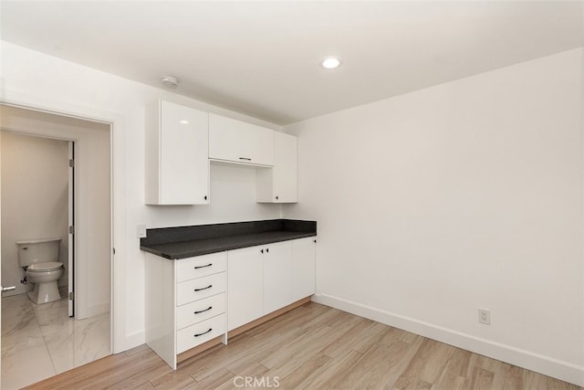 kitchen featuring baseboards, dark countertops, white cabinetry, recessed lighting, and light wood-type flooring