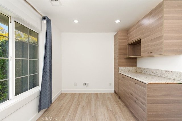 kitchen with light wood-style flooring, baseboards, recessed lighting, light brown cabinets, and modern cabinets