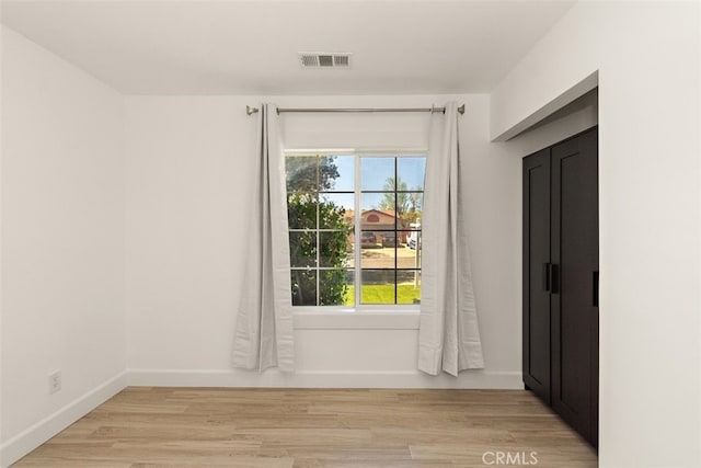 empty room featuring plenty of natural light, baseboards, and light wood-style floors