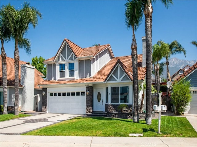 view of front of property with a tiled roof, concrete driveway, stone siding, a front lawn, and a garage