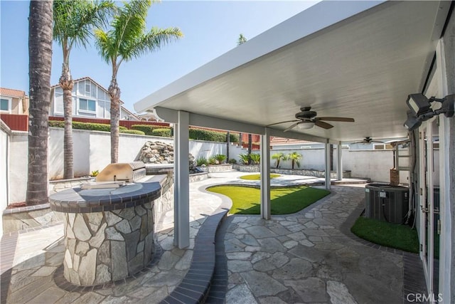 view of patio / terrace with a fenced backyard, central AC, a ceiling fan, exterior kitchen, and a water view