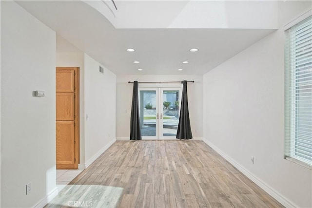 empty room with light wood finished floors, recessed lighting, french doors, and baseboards